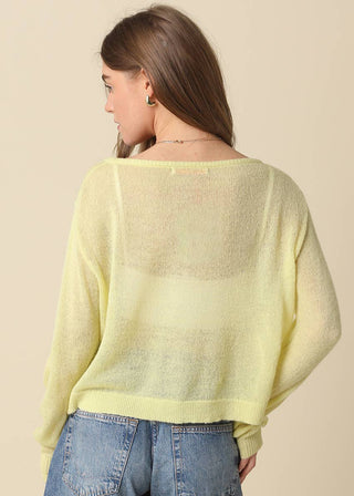 Woman wearing a light yellow sweater and blue jeans against a beige background
