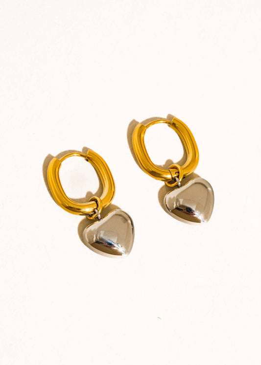 Gold hoop earrings with heart-shaped charms on a white background