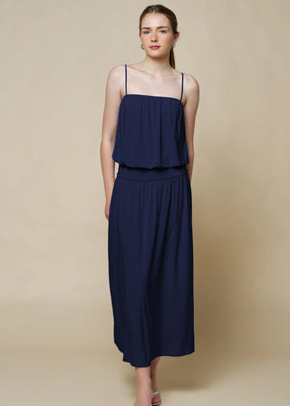 Woman wearing a navy blue dress against a beige background