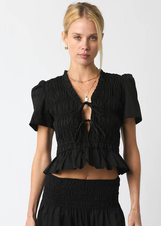 Woman wearing a black ruffled top against a white background