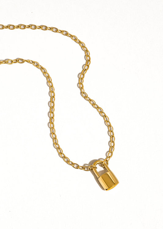 gold necklace with lock charm on white background