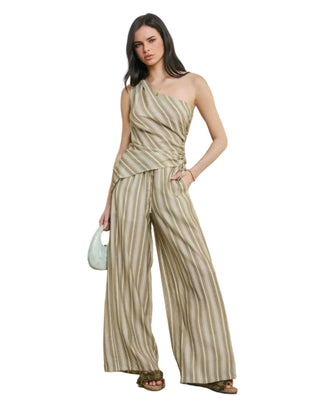 A woman models a one-shoulder striped jumpsuit with wide legs in a beige and brown colorway, standing against a neutral textured wall.