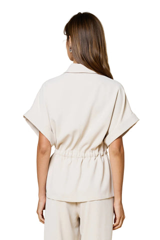 Woman wearing a beige top and pants against a beige background
