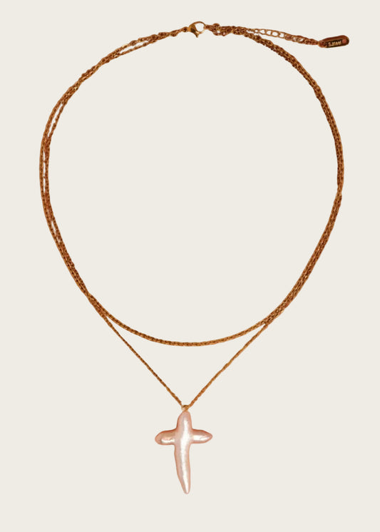 Gold necklace with a cross pendant on an orange background