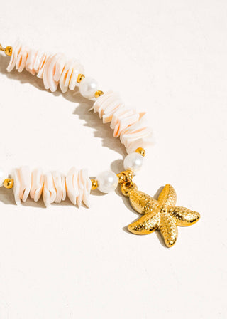 Necklace with shell beads and a gold starfish charm on a white background