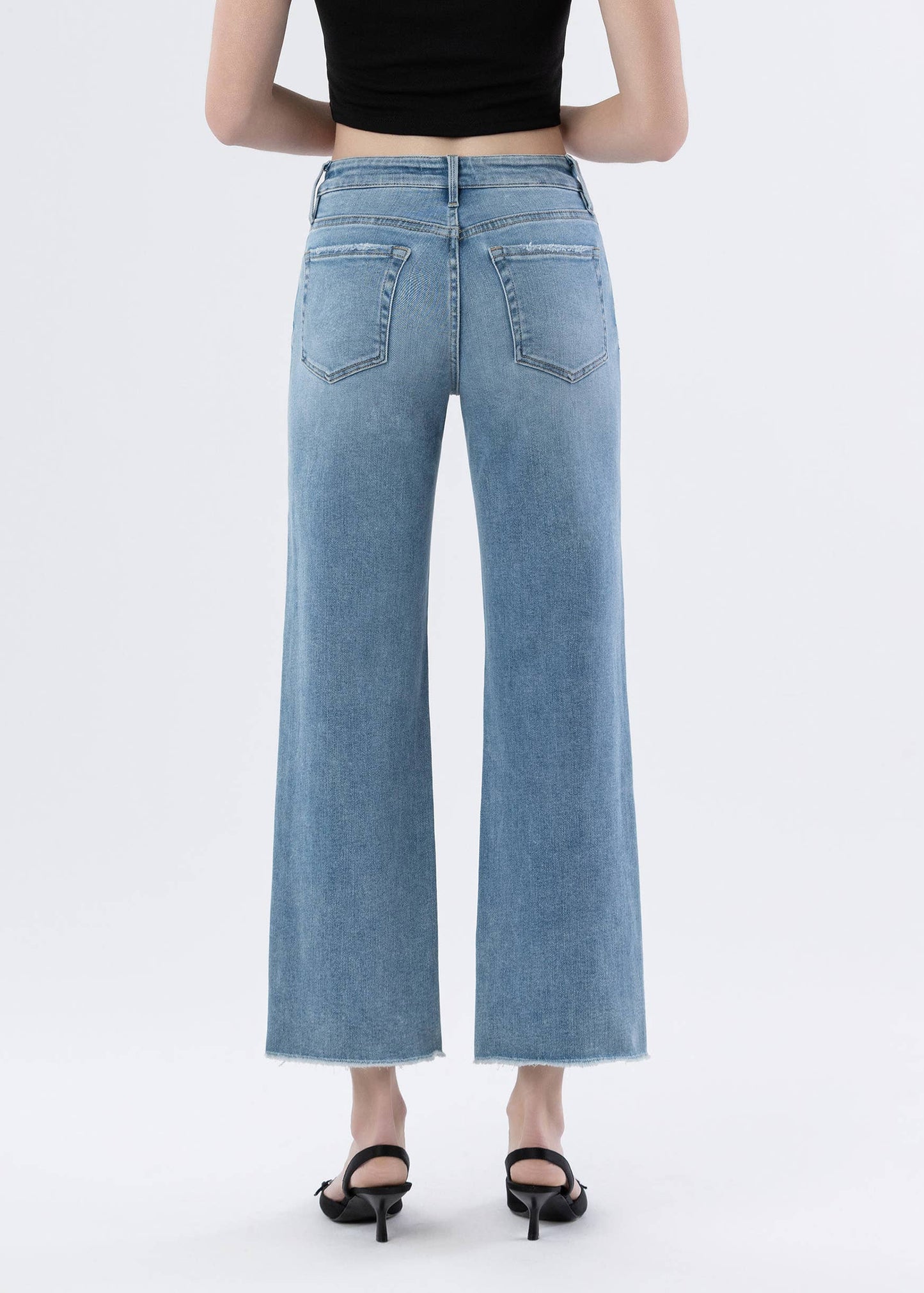 Person wearing light blue jeans on a white background