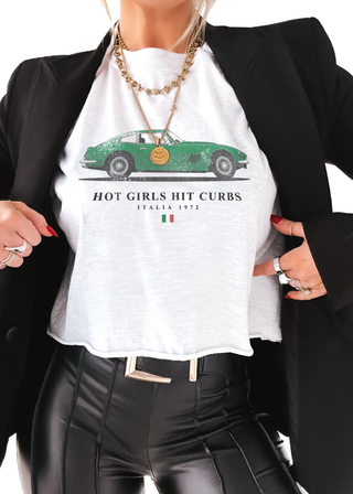 Person wearing a white t-shirt with a green car graphic and text, paired with a black blazer and leather pants.