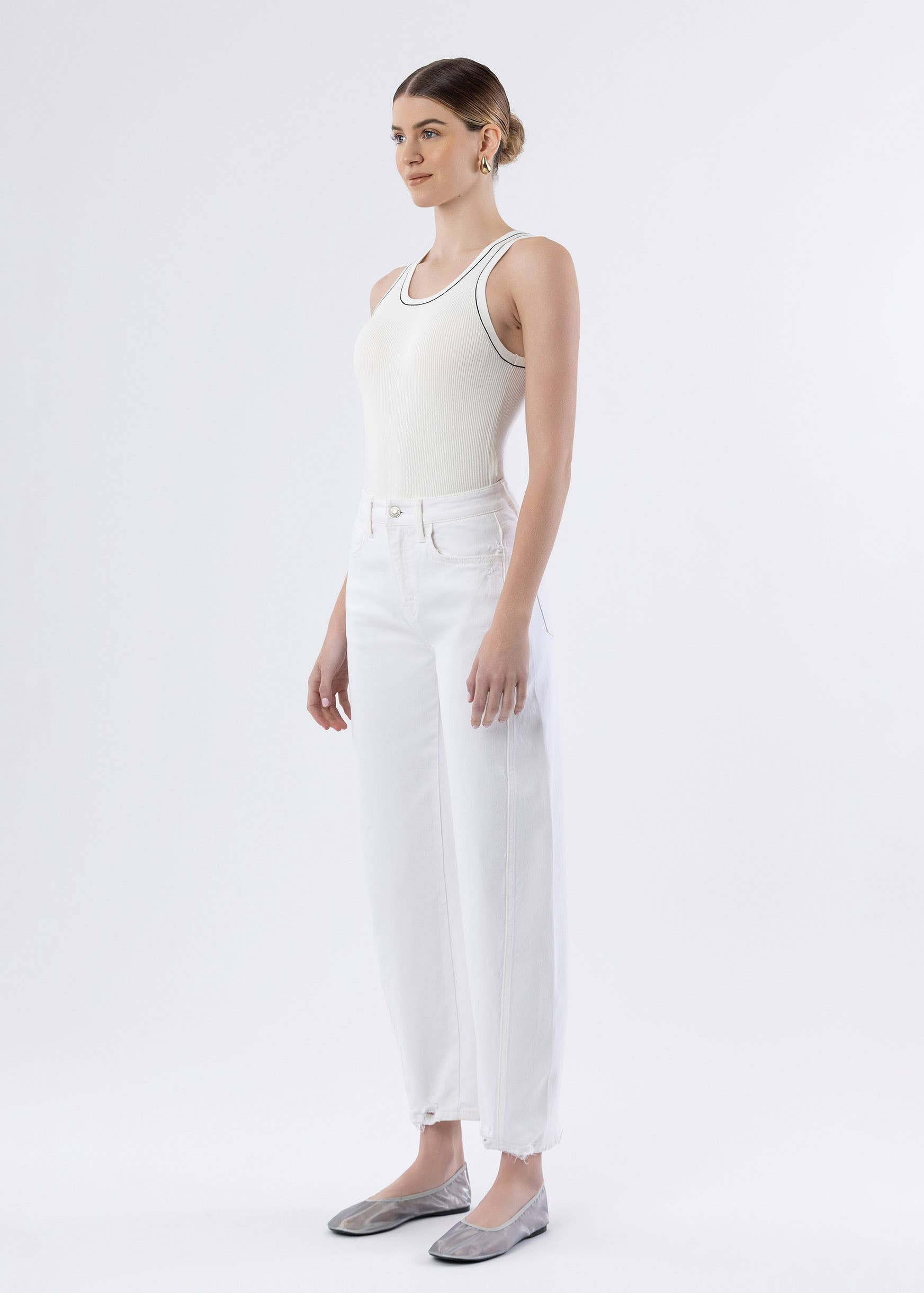 Woman wearing a white sleeveless top and pants on a white background