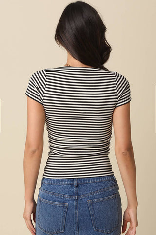 Person wearing a navy and white striped shirt with a beige background