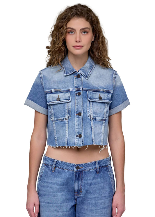 Woman wearing a denim jacket and jeans against a gray background