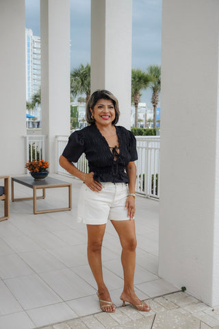 women wearing white denim shorts and black top with tropical background