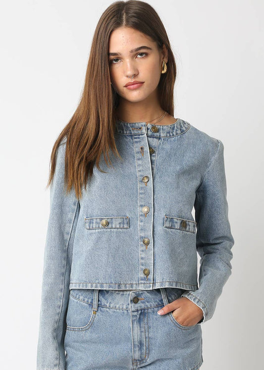 Woman wearing a light blue denim jacket and shorts on a white background