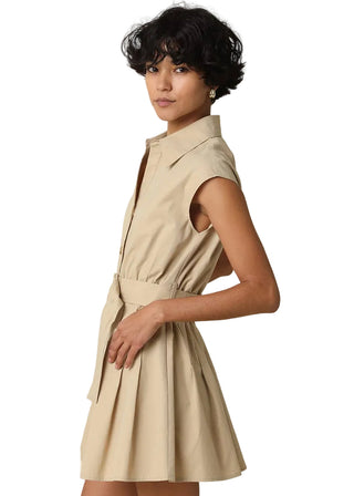 Woman wearing a beige sleeveless dress against a plain background