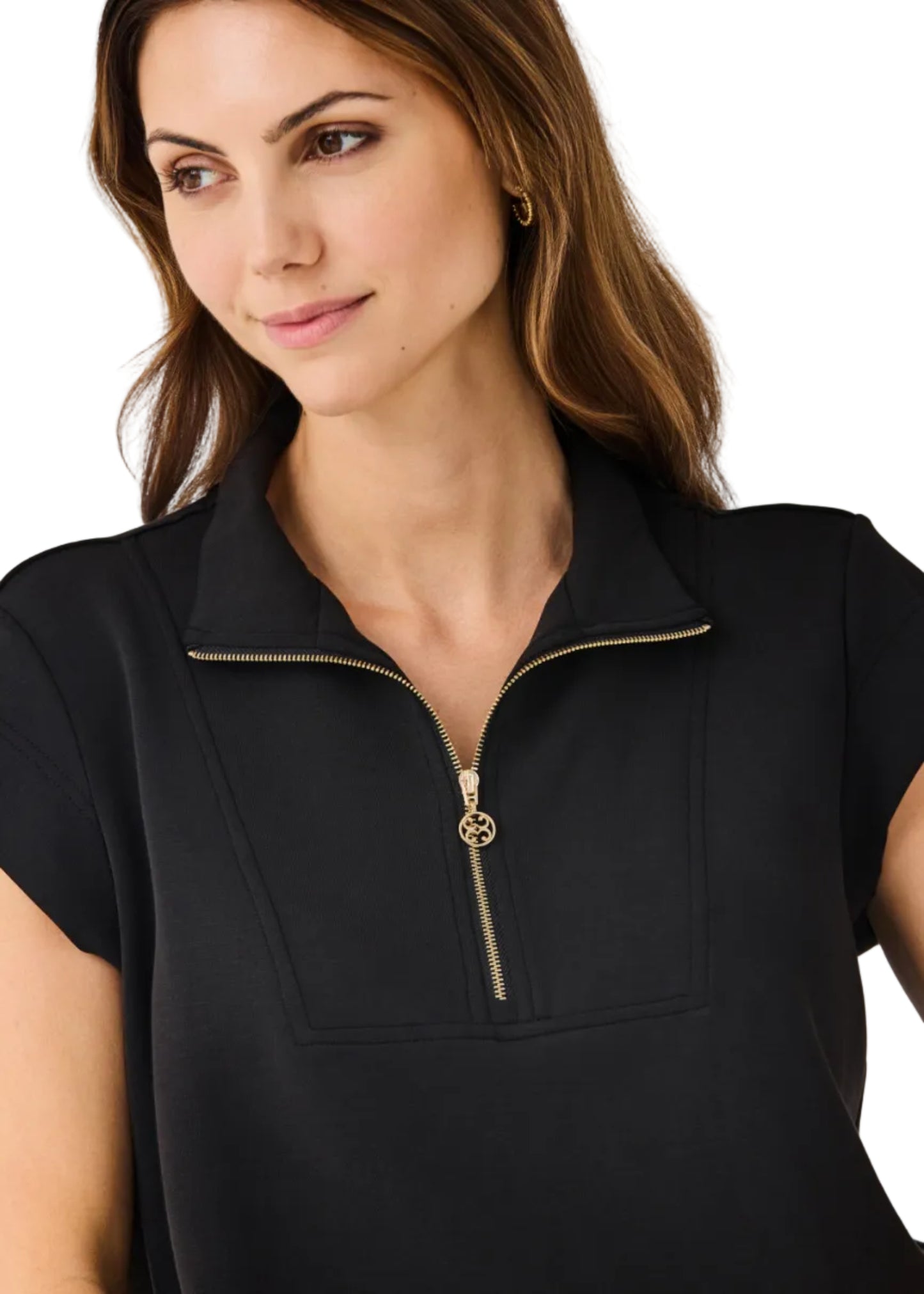 Woman wearing a black top with a gold zipper on a plain background