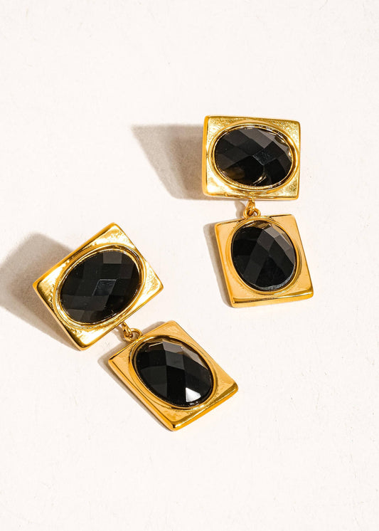 Gold earrings with black stones on a white background