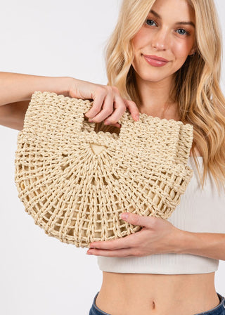 Woman holding a beige woven handbag against a white background