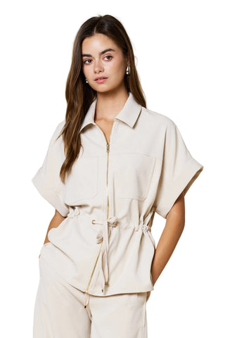 Woman wearing a beige outfit against a beige background