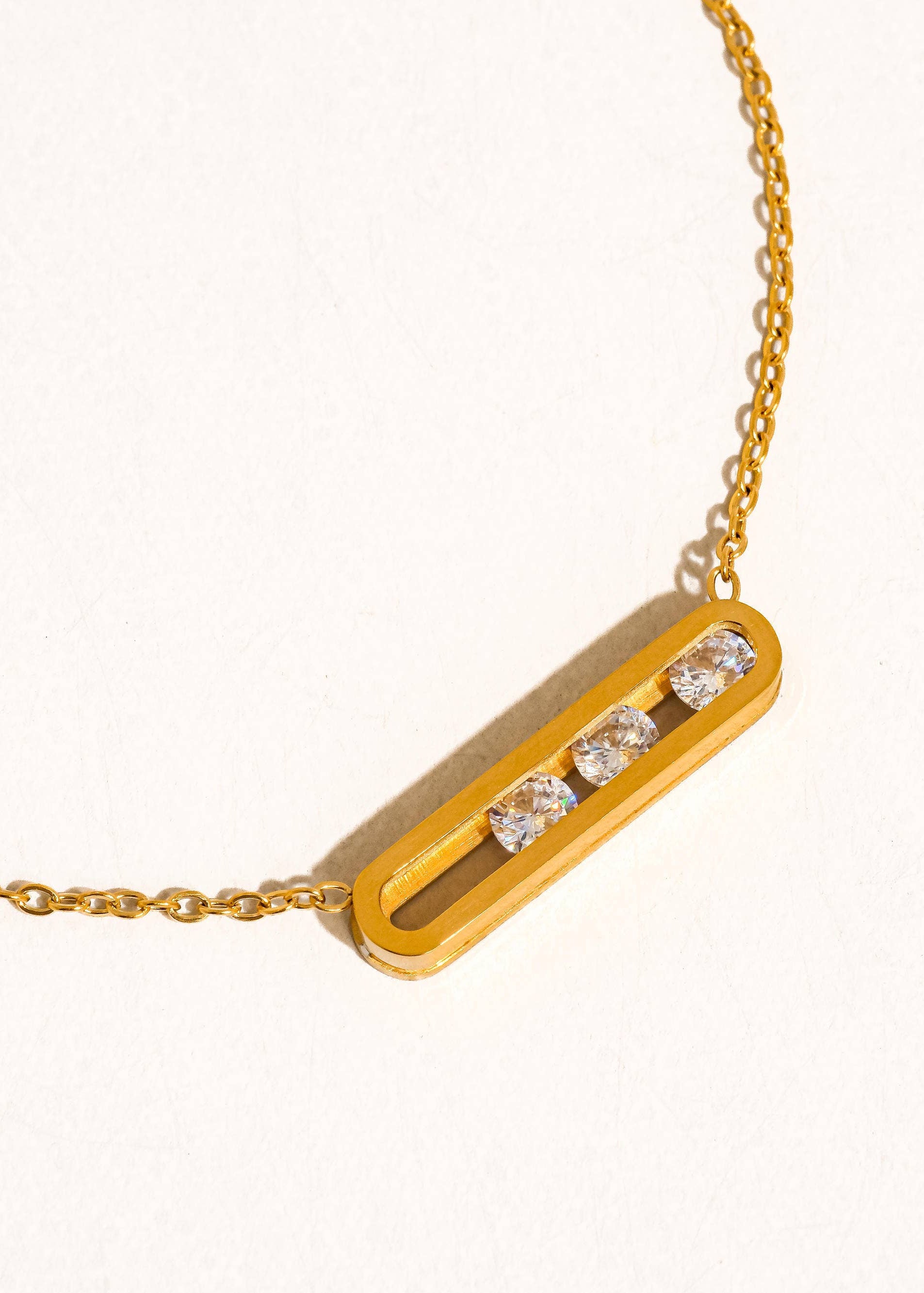 Gold necklace with a bar pendant featuring diamonds on a white background