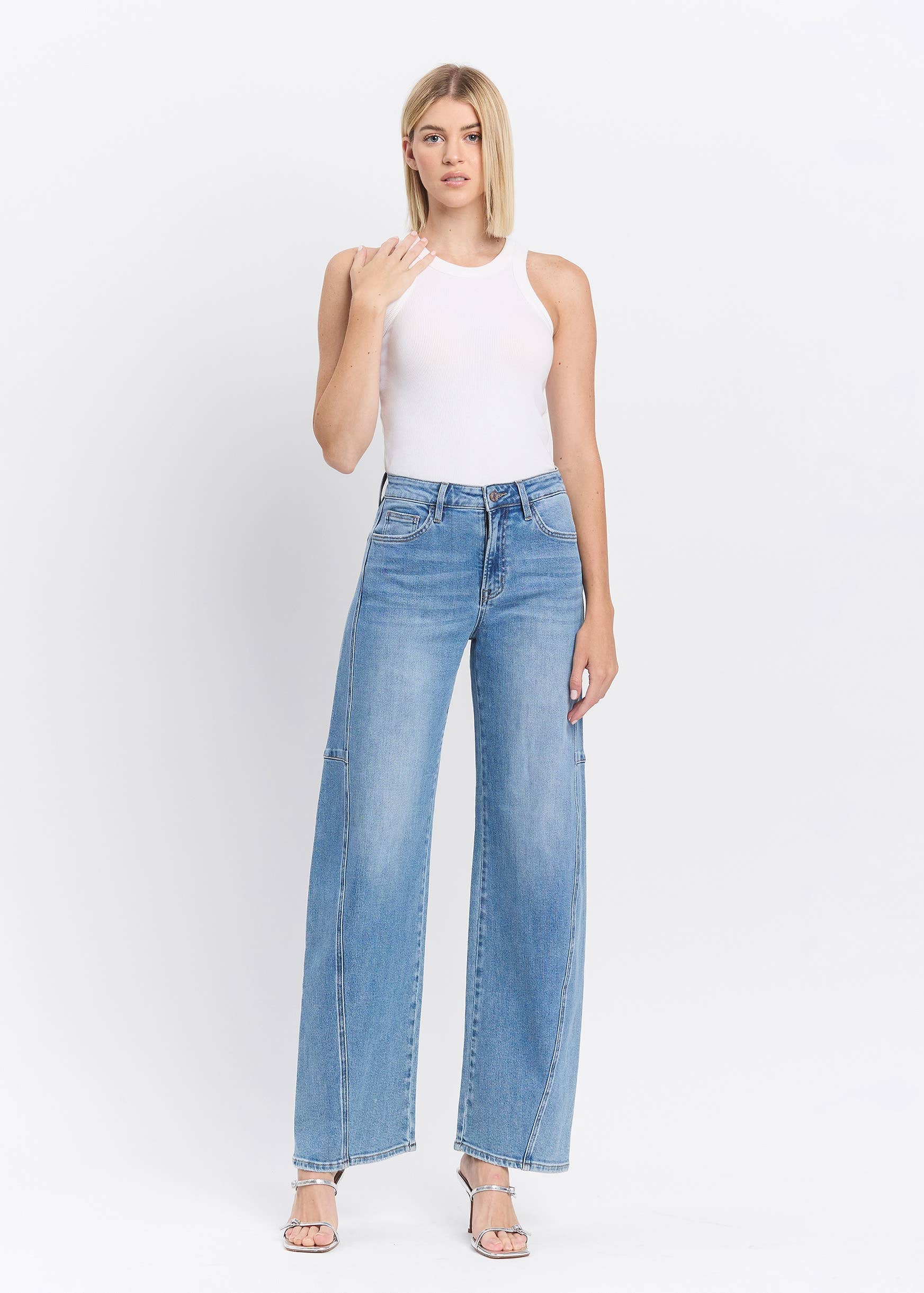 Woman wearing light blue jeans and a white top on a white background