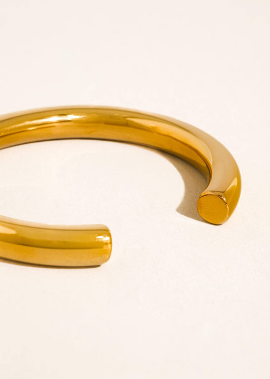 Gold bangle on a light beige background