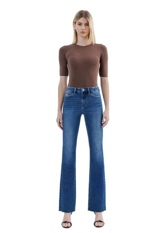 Woman wearing a brown top and blue jeans on a white background