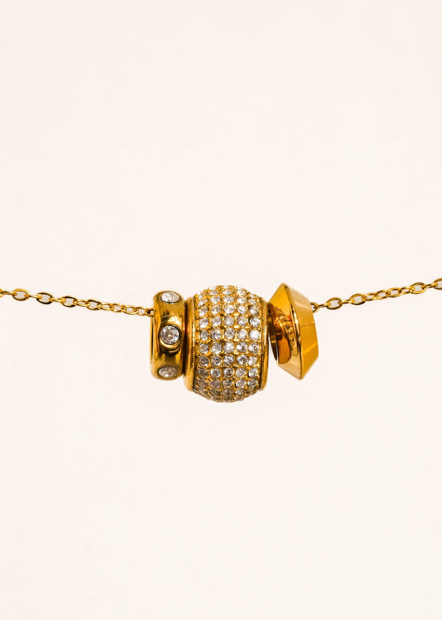 Gold necklace with a large, ornate bead on a white background