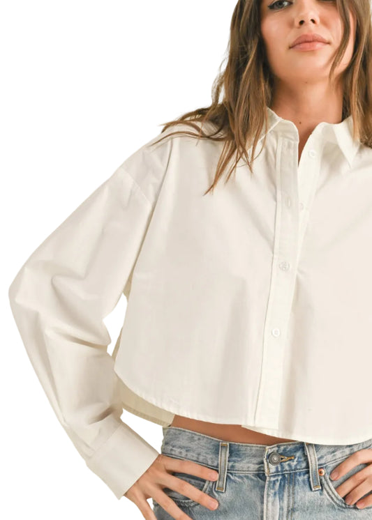 Woman wearing a white button-up shirt and blue jeans against a beige background