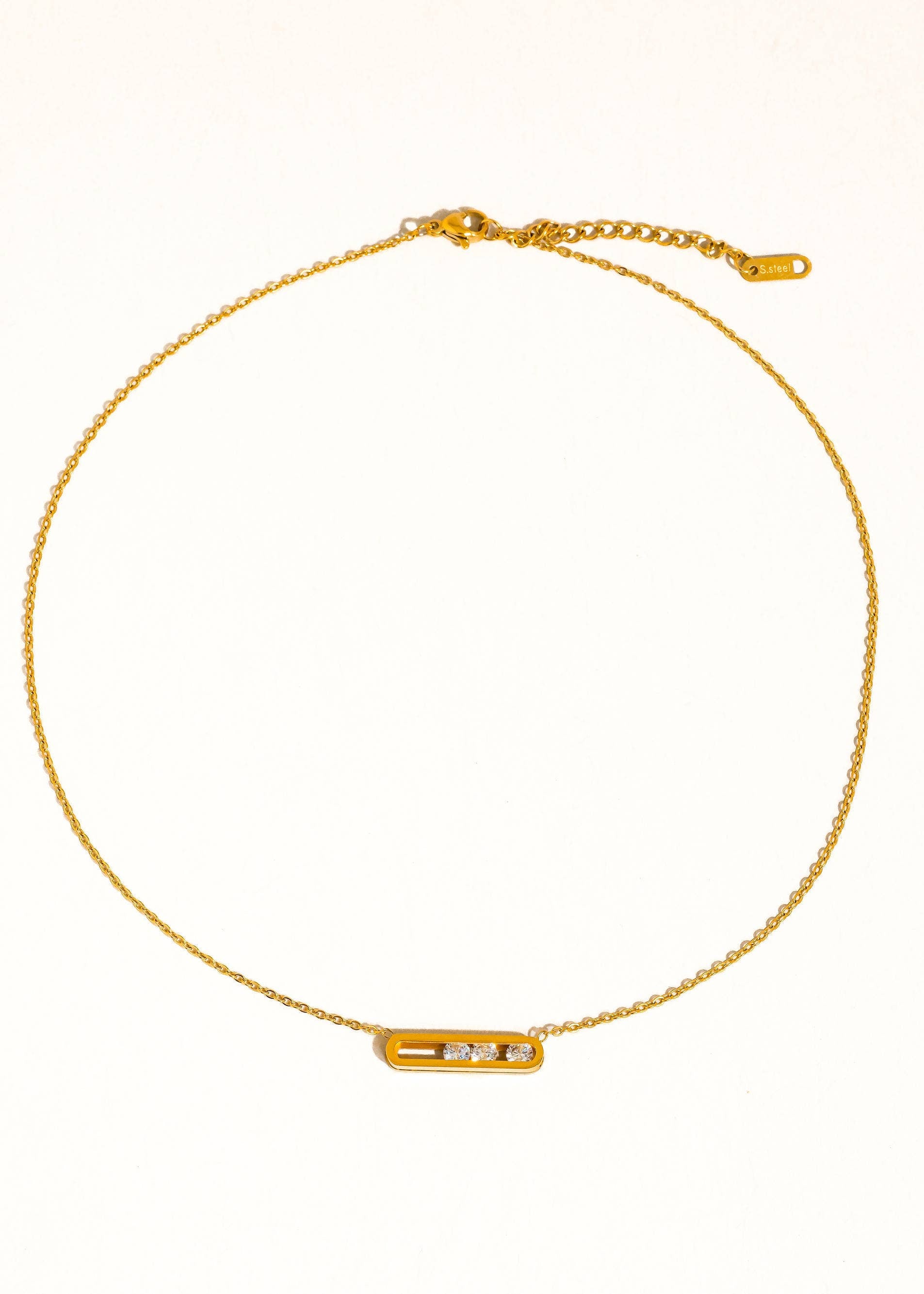 Gold necklace with a small rectangular pendant on a white background