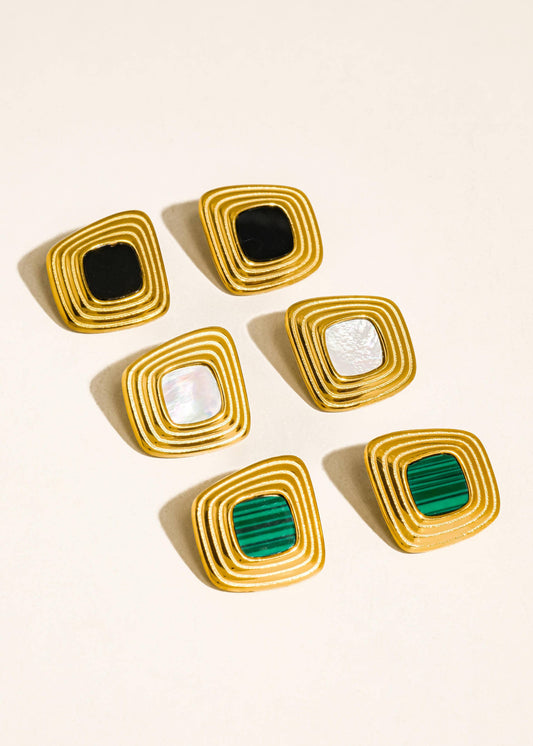 Set of six square-shaped earrings with colored centers on a beige background