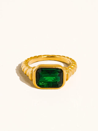 Gold ring with a green gemstone on a white background