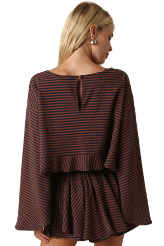 A woman shown from the back wearing a dark striped long-sleeve top and matching skirt against a plain beige studio background.