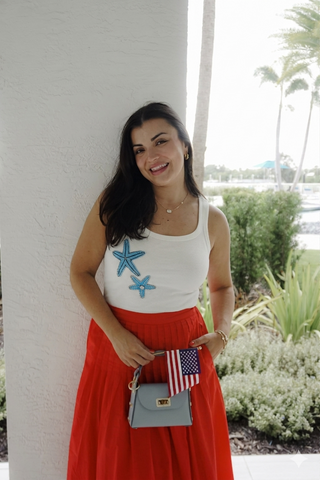 women in white tank with blue starfish coastal background
