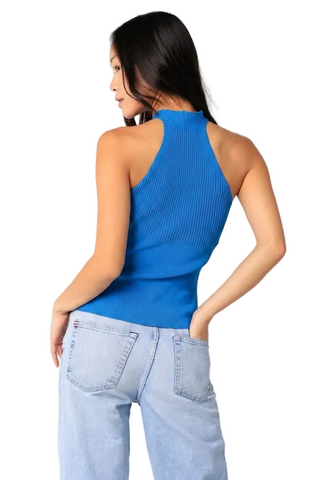 Woman wearing a blue sleeveless top and light blue jeans on a white background