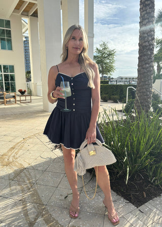 Woman in a navy dress holding a glass of lemonade outdoors.