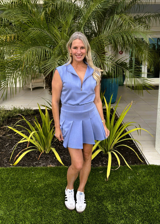 Woman in a blue dress standing in front of green plants