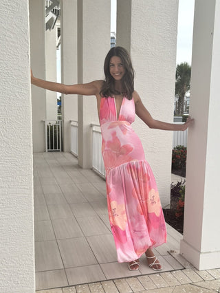 Woman wearing a pink floral dress standing on a patio.