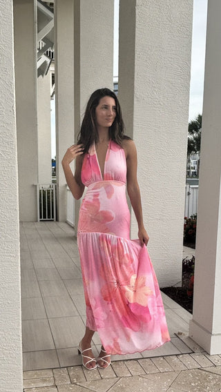 Woman wearing a pink floral dress standing on a patio.