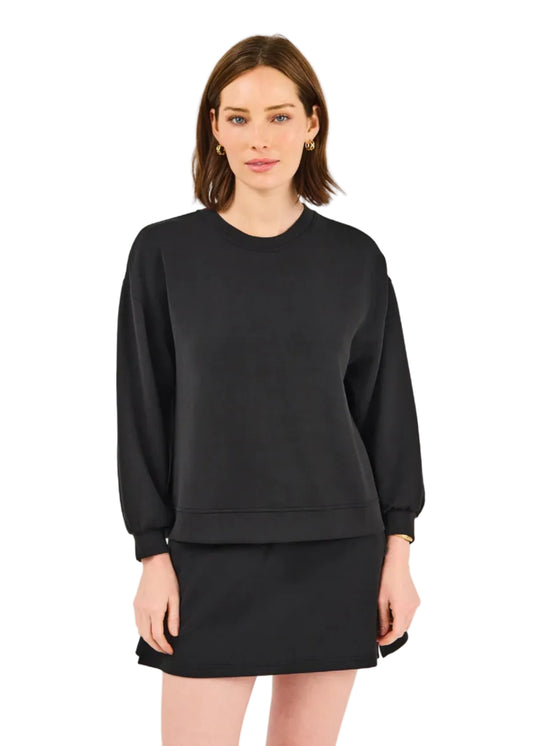 Woman wearing a black sweatshirt and skirt set on a light gray background