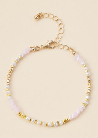 Gold and pearl bracelet on a beige background