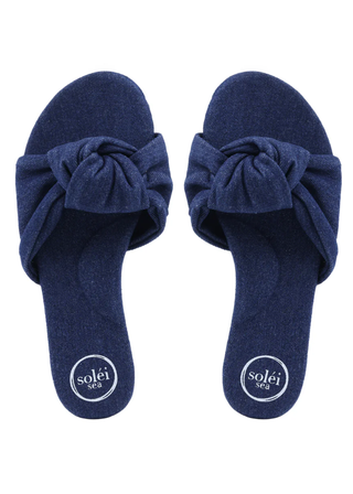 Pair of navy blue slippers with bow details on a white background