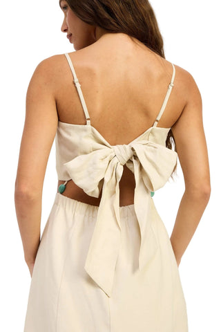 Woman wearing a beige dress with a bow detail on a white background