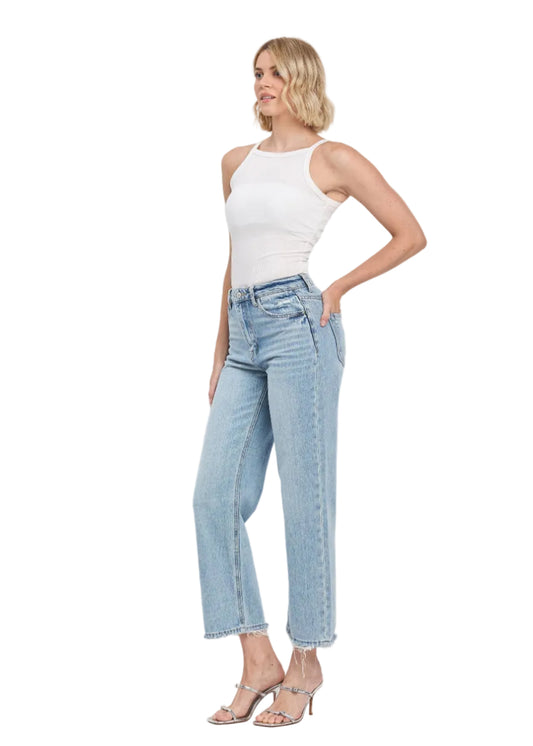 Woman wearing light blue jeans and a white top on a white background