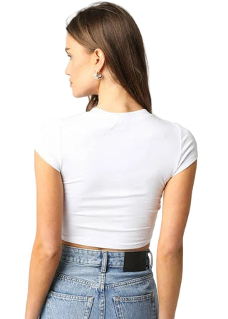 Woman wearing a white crop top and blue jeans on a plain background