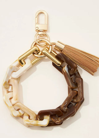 Gold and brown chain keychain with tassel on a light beige background
