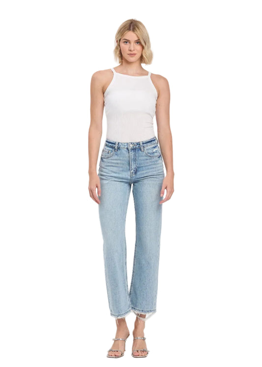 Woman wearing light blue jeans and a white top on a white background