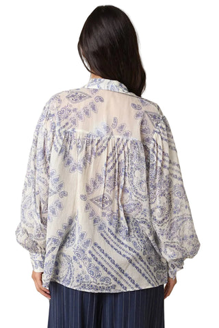 Person wearing a patterned blouse with a beige background