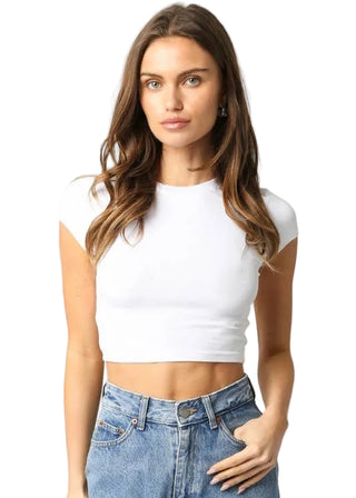 Woman wearing a white crop top and blue jeans on a plain background