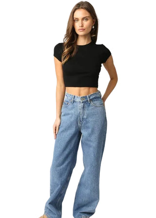 Woman wearing a black crop top and blue jeans on a white background