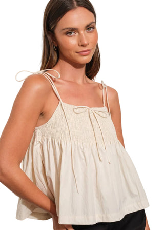 Woman wearing a beige sleeveless top against a white background