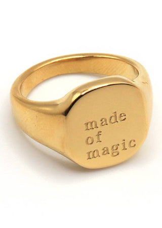 A gold-plated stainless steel signet ring with the inscription 'MADE OF MAGIC' embossed on the top surface.
